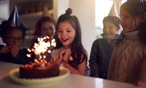 Girl Celebrating Birthday With Group Of Friends At Home Being Given Cake Decorated With Sparkler - Stock Photo - Images