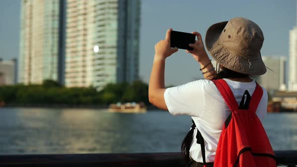 Young Asian women tourists take photos beside the river in Bangkok Thailand before sunset.