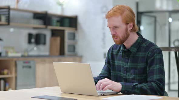 Beard Redhead Man Reacting to Loss on Laptop in Cafe alt