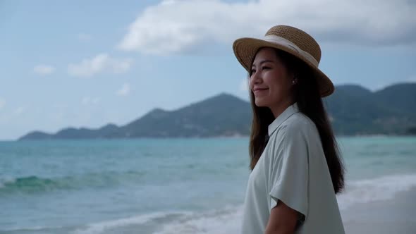 Slow motion of a beautiful young asian woman with hat on the beach