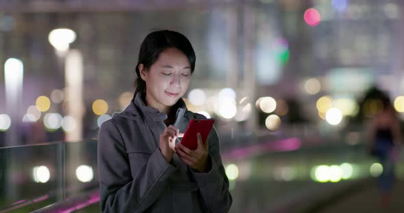 Woman use of cellphone online in the city at night alt