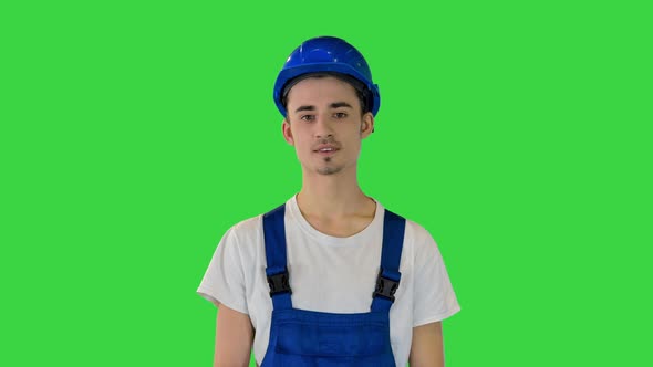Young Construction Worker Smiling on Camera with Hands on His Hips on a Green Screen Chroma Key