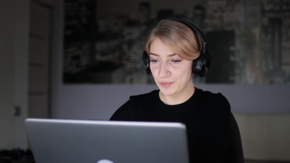 Beautiful Woman in Headphones Talking with Business Partners Via Video Chat