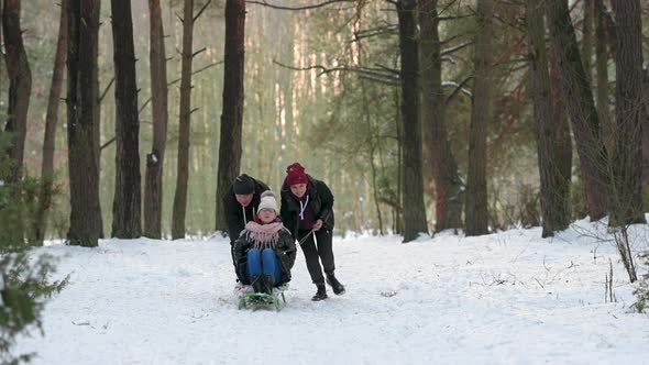 Happy family sledding in a beautiful snowy park.