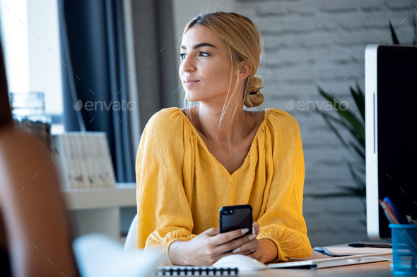 happy freelance business woman seller texting with her mobile phone while working with computer