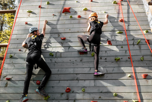 Man and woman climbing the wall in the park
