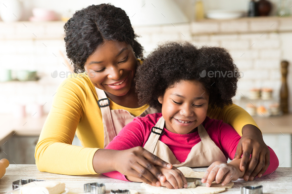 Joyful little african american girl making cookies for her family Stock  Photo by Prostock-studio