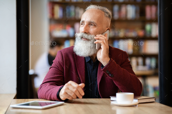 Busy aged businessman talking on phone at cafe Stock Photo by 