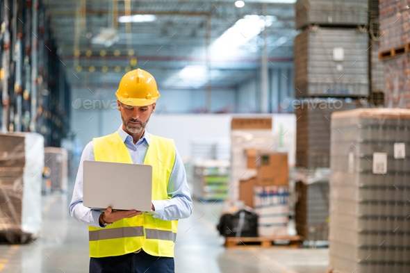 Warehouse manager with laptop entering inventory data to database - Stock Photo - Images