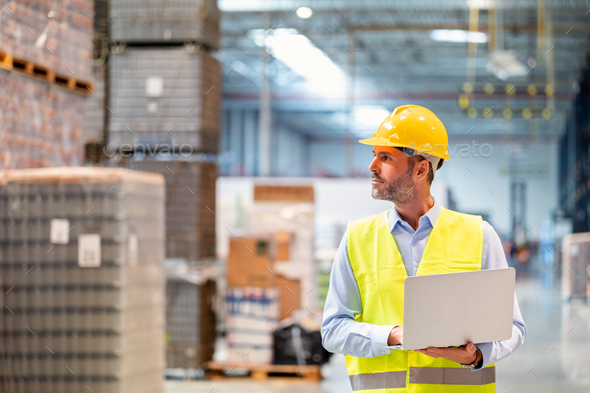 Warehouse manager with laptop entering inventory data to database - Stock Photo - Images
