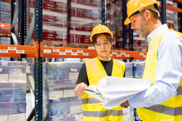 Warehouseman and manager talking about plans of inventory in large warehouse - Stock Photo - Images
