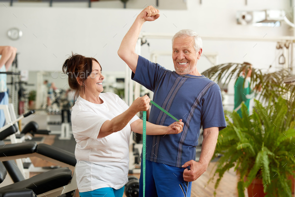Funny senior man flexing his muscles at gym Stock Photo by stockfilmstudio