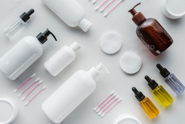 flat lay with bottles of cream, natural oils and cosmetic pads on white surface, beauty concept
