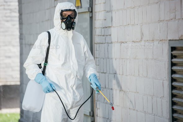 Pest Control Worker In Respirator Spraying Pesticides With Sprayer On Building Wall Stock Photo By Lightfieldstudios