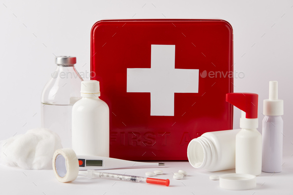 close-up shot of red first aid kit box with various medical bottles and supplies on white