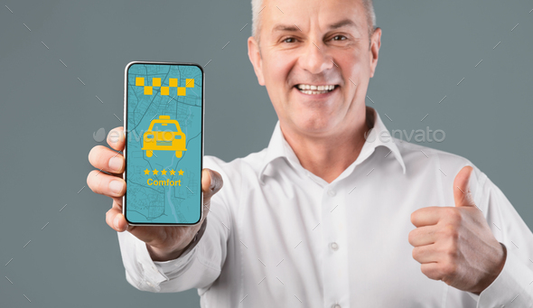 Handsome black guy holding smartphone with opened taxi services mobile app, yellow background