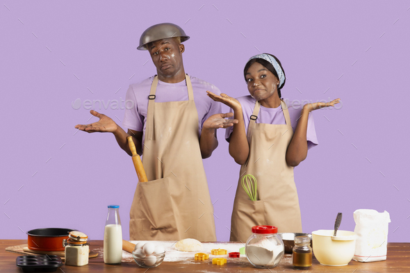 Confused black couple covered in flour shrugging, dont know how to cook, standing puzzled on violet