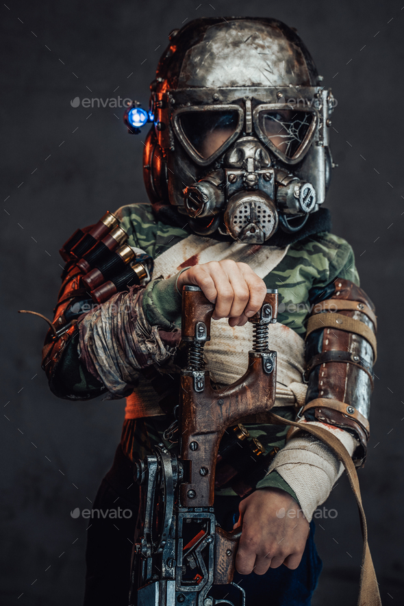 Armed with riffle little boy with gas mask in dark background Stock