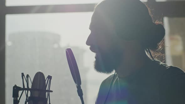 A Young Male Radio Presenter Reads a Text in Front of a Microphone alt
