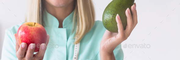 Beautiful nurse holds apple and avocado, healthy diet plan concept - Stock Photo - Images