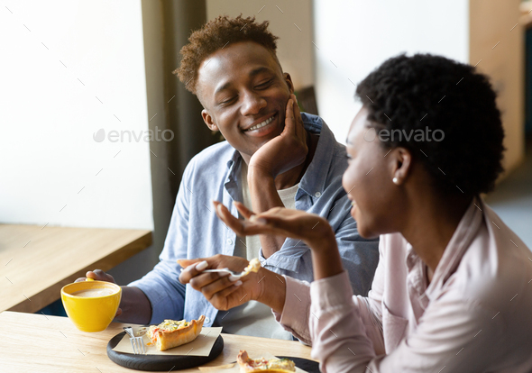 Romantic black couple having conversation at dinner in cozy cafe