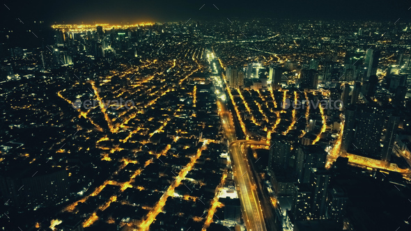 Illuminate streets of Manila downtown cityscape at night. Aerial traffic city route. Urban transport