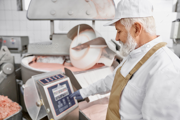 Worker standing near equipment for grinding meat
