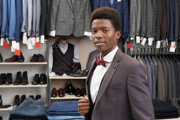 African man posing in boutique in white shirt, stylish suit