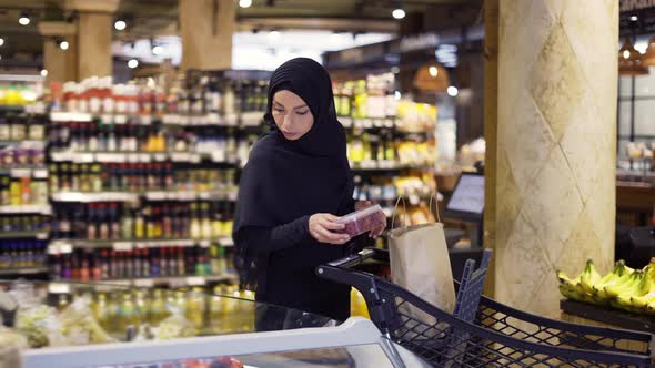 Muslim Woman Shopping for Groceries Taking Some Berries From the Fruit Aisle alt