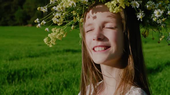 Portrait of Happy Smiling Caucasian School Age Girl with Her Eyes Closed in the Sun with a Wreath of