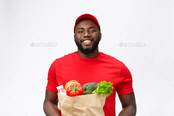 Delivery Concept - Handsome African American delivery man carrying package grocery food and drink