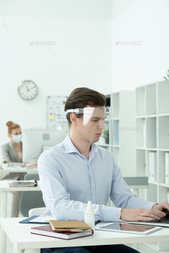 Young businessman in protective screen on head and formalwear networking