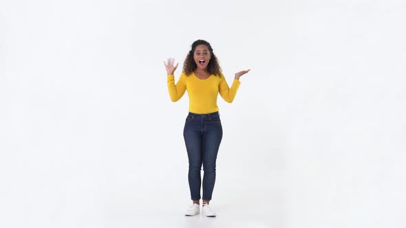 Smiling surprised young African American woman waving her hand and jumping with joy