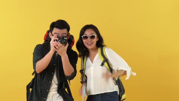 Happy Asian backpacker couple taking photo together and doing bravo gesture