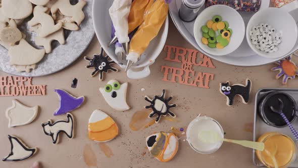 Step by step. Mother and daughter decorating Halloween sugar cookies with colorful royal icing. alt