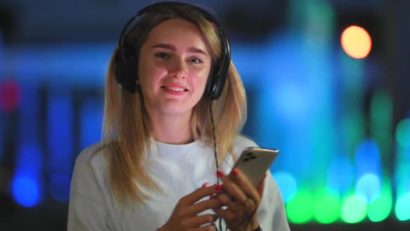 Portrait of a Young Girl with Phone and Headphones Listens to Music 