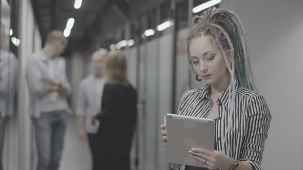 Portrait of Beautiful Young Caucasian Woman Using Tablet and Drinking Coffee in Office Corridor with alt