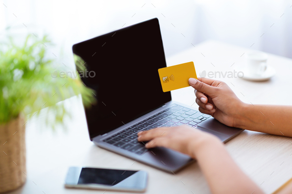Black lady using laptop and credit card at home