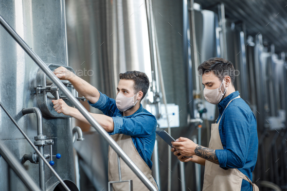 Workers at brewery and fermentation of beer to produce beverage - Stock Photo - Images