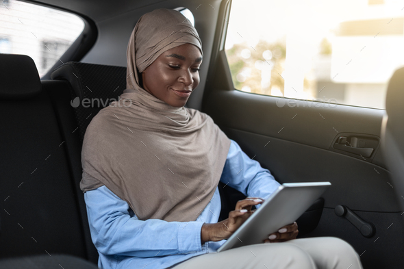 African islamic businesswoman using digital tablet while having trip by car