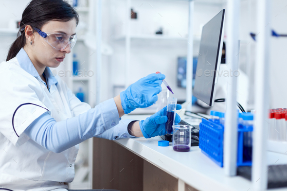Woman scientist in lab during clinic experiement taking sample of genetic material