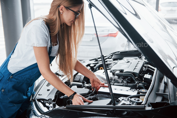 You can see all the details. On the lovely job. Car addicted woman repairs black automobile indoors