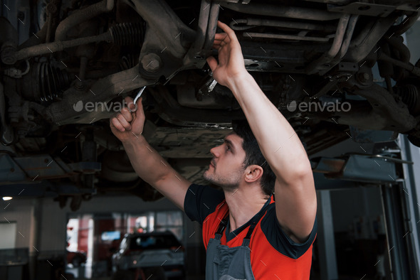 Easy job for this guy. Man at the workshop in uniform fixes broken parts of the modern car