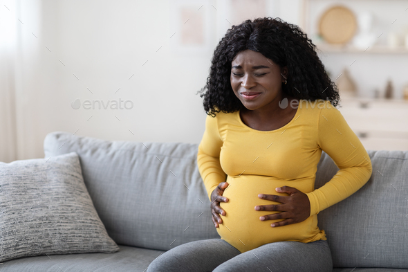 Black pregnant woman suffering from labor pains at home