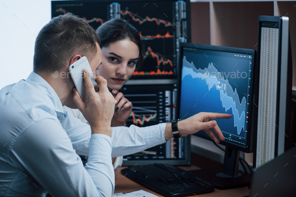 Team of stockbrokers are having a conversation in a office with multiple display screens - Stock Photo - Images