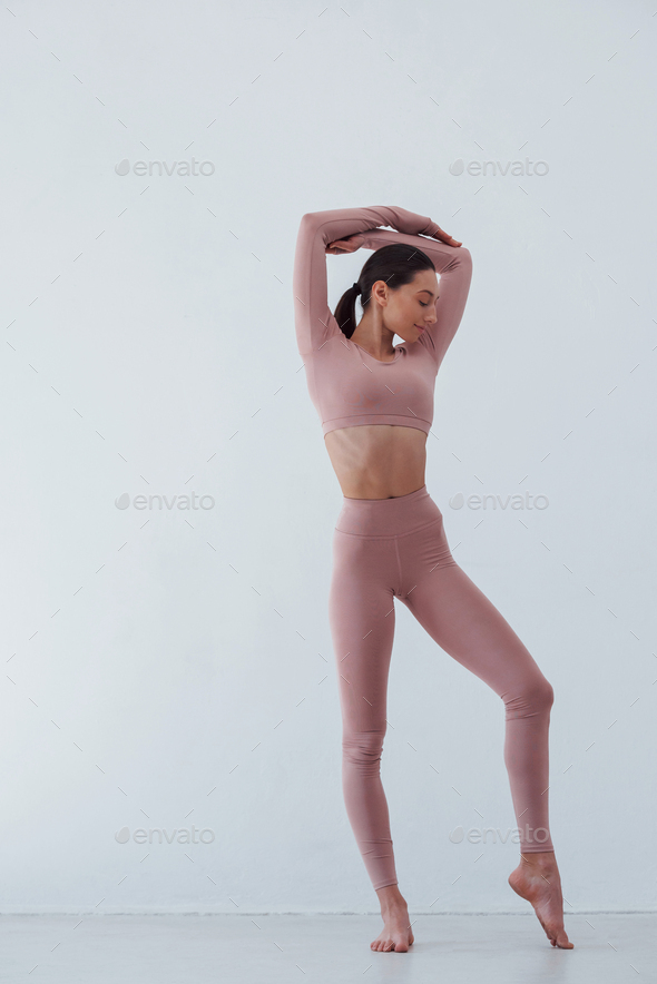 Skinny body type. Caucasian pretty woman doing exercises against white background in the studio