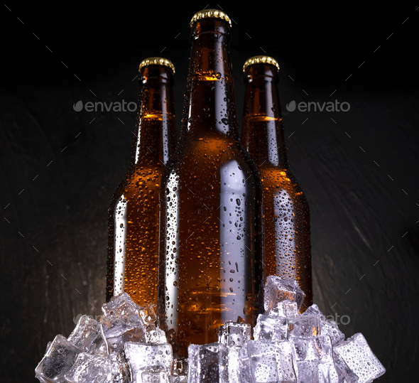 Cold beer bottle with drops, frost and vapour on black Stock Photo