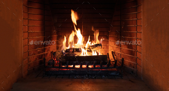 Christmas time, cozy fireplace. Wood logs burning, fire bricks