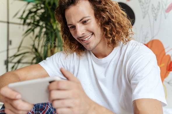 Caucasian handsome happy guy playing video game on mobile phone