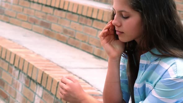 Worried schoolgirl sitting in campus alt